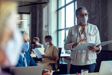 Black businesswoman wearing mask in office meeting