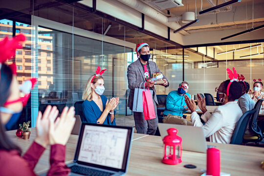 Colleagues exchanging Christmas gifts in office during holiday celebration