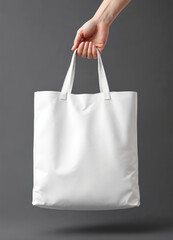 Hand holding a blank white tote bag on a dark background, eco-friendly reusable fabric shopping bag for branding and advertising.