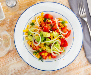 Popular all over the world appetizing vegetable salad of tomatoes, avocado, canned corn and onion, cut into rings