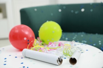Confetti poppers, serpentine streamers and other party decor on white table indoors, closeup