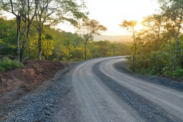 Fototapeta premium Landscape of gravel road in countryside with meadow. Road in rainy season