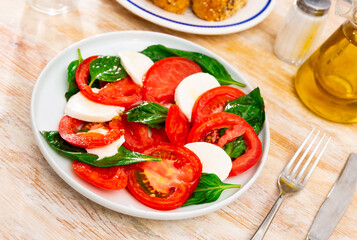 Delicious fresh vegetable caprese salad with tomato and mozzarella served on plate