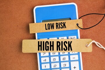 calculator and paper tags with the words low risk or high risk. prognosis and receive less intensive treatment than those in the two higher-risk groups