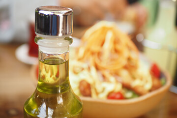 Fresh olive oil bottle in front of a colorful pasta salad