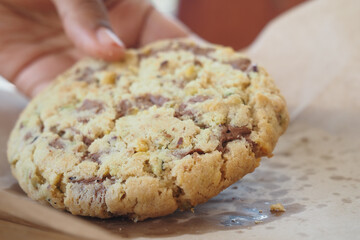 Freshly baked chocolate chip cookie being picked up from parchment