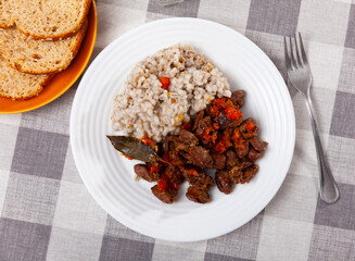 Traditional dish of Russian cuisine is pearl porridge with stewed chicken hearts with vegetables. Served with bread