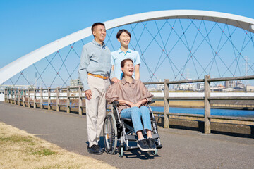 夫と車椅子に乗った妻と介護士　屋外　ポートレート
