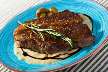 Fried beef steak with mushrooms sauce branch of rosemary at colored plate