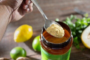 A view of a hand holding a spoon full of chicken bouillon powder.