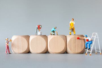 Miniature people ,Painters dressed as painters creatively painting large wooden blocks