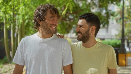 Two men smiling together outdoors in a city park, showcasing a warm brotherly relationship and friendship in an urban setting