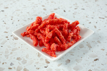 A view of a saucer of popular spicy cheesy crunchy chips.