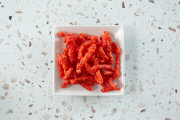 A top down view of a saucer of popular spicy cheesy crunchy chips.