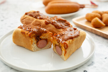 A view of a plate of chili dogs, featuring one that is cut in half.