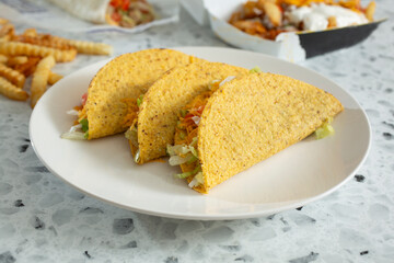 A view of three hard shell tacos on a plate.