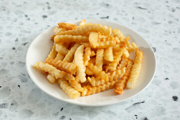 A view of a plate of crinkle cut french fries.