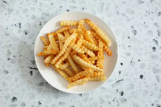 A top down view of a plate of crinkle cut french fries.