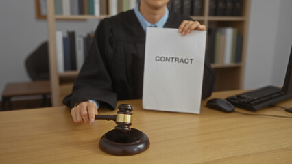 Woman holds a contract at a lawyer's office, displaying a gavel on the desk, showcasing a...
