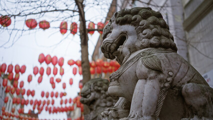 Fototapeta premium Chinatown street in london with stone lion statue and red lanterns hanging in winter.