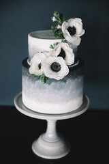 Elegant two-tiered cake decorated with white flowers against a dark backdrop for celebrations © tisaeff