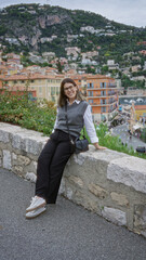 Fototapeta premium Woman smiling in villefranche france with picturesque mediterranean backdrop featuring colorful architecture and lush hills