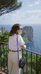 Fototapeta premium Woman enjoying view outdoors in capri italy overlooking beautiful blue sea and rocky landscape against bright summer sky from scenic vantage point