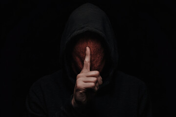A person is standing in a dark room with a hood over their head