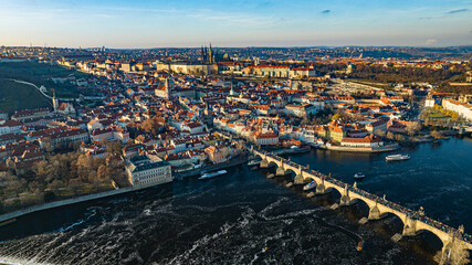 Prague, Czech Republic - Aerial panoramic drone view of the world famous Charles Bridge (Karluv most) and St. Francis Of Assisi Church with a beautiful winter sunset. St. Vitus Cathedral at background