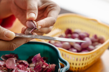 hand peeling shallot with a knife in a kitchen