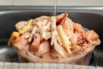 Rinsing chicken parts under running water, home cook food preparation