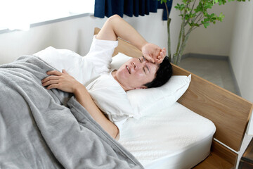 睡眠中に苦しそうな表情をするアジア人男性