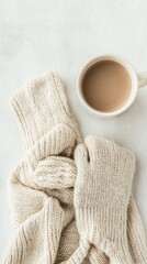 Cozy knitted mittens and a warm cup of coffee on a soft light background for autumn or winter season