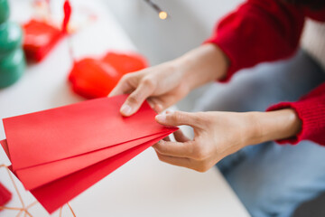 Asian Woman giving red envelope for Lunar New Year celebrations. Hand hold red packet