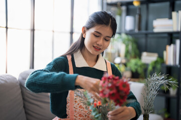 Happy asian Woman arranging flowers caring for home greenery
