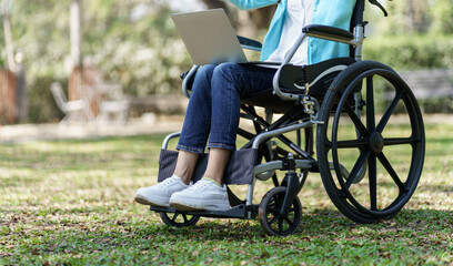 Obraz premium Young asian woman in wheelchair working with laptop