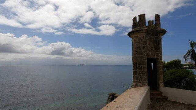 A scenic view of a castle tower overlooking the beach, with clear skies and calm ocean