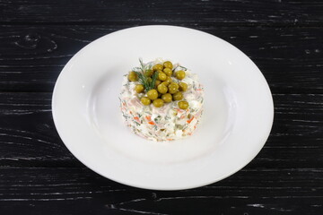 salad with vegetables, mayonnaise and green peas. Olivier salad on a plate