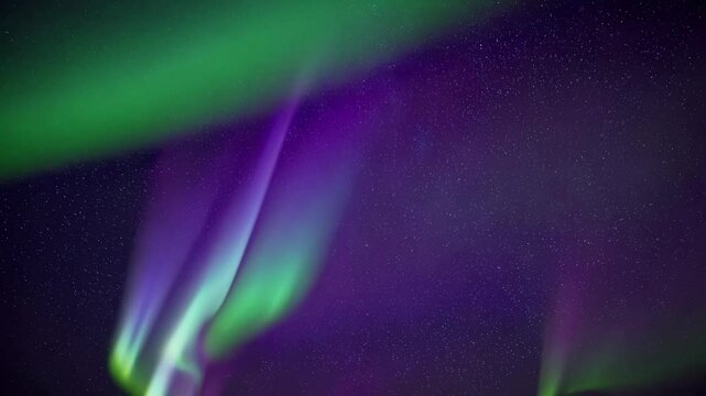 A mesmerizing video capturing the vibrant colors of the Northern Lights dancing across a starry sky, filmed from a low-angle camera angle.
