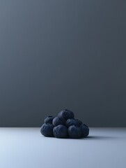 A small pile of blueberries sits on a light gray surface against a dark gray background.