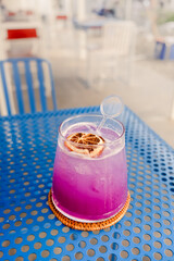 Closeup image of pretty dewy fresh iced cold sparkling purple butterfly pea soda drink served in a...