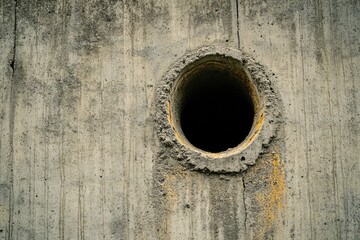 A concrete wall with a hole allowing access or escape