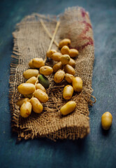 Close up of  unripe yellow color date fruits placed on a grunge background. Rustic food photography of dates. Middle eastern sacred fruit - dates,  freshly plucked from the tree.
