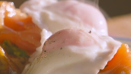 Ultra Slow Motion of Pepper Falling on Breakfast of Avocado Crumpet with Smoked Salmon Topped with Poached Egg. Morning High Protein Healthy Stylish Food Brunch Footage 4K. - Powered by Adobe