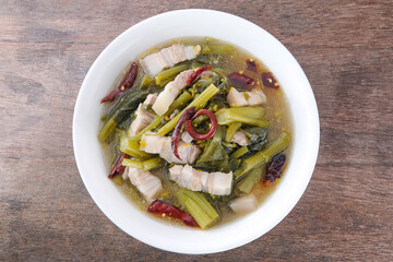 Cabbage screen with pork belly in a white ceramic bowl on a wooden table. Chinese Cabbage Soup.