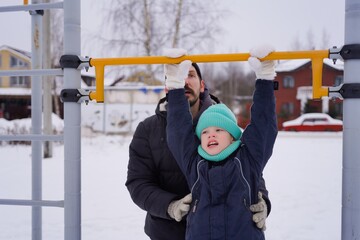 Obraz premium A father and son enjoy a fun winter activity outdoors, tubing down a snowy hill. The photo captures their joyful smiles, bonding moments, and the excitement of a thrilling winter sport