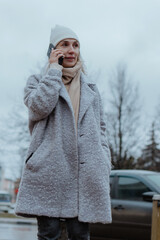 Smiling young woman walking through a frosty city street on a winter morning, talking on her...
