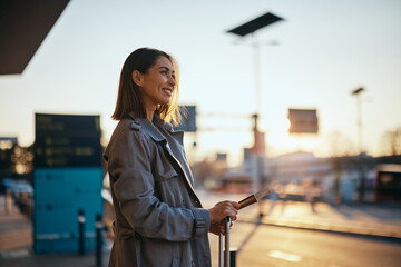 Happy woman waiting for cab at airport at sunset.