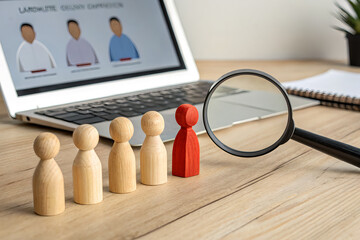 Fototapeta premium Red wooden figure standing out among wooden figures on table