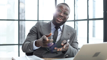 A businessman man in a close-up in a jacket speaks to the camera in the office